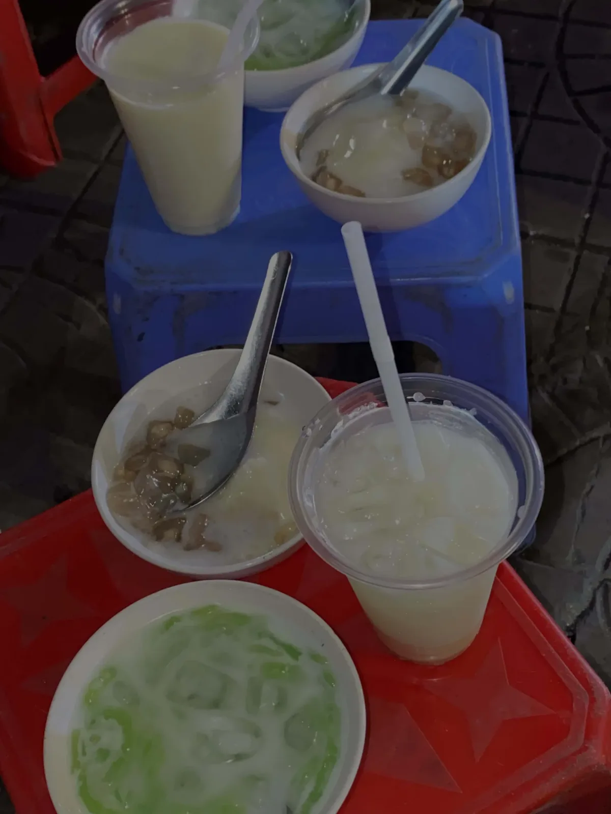Bowls of Vietnamese sweet tofu dessert with coconut milk and plastic cups of iced soy milk served on small plastic stools. (Source: nhuthuy)
